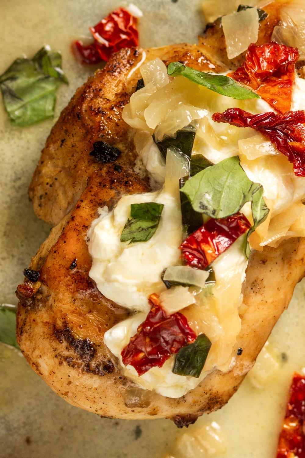 A piece of chicken that's topped with cheese, basil, and sun dried tomatoes.