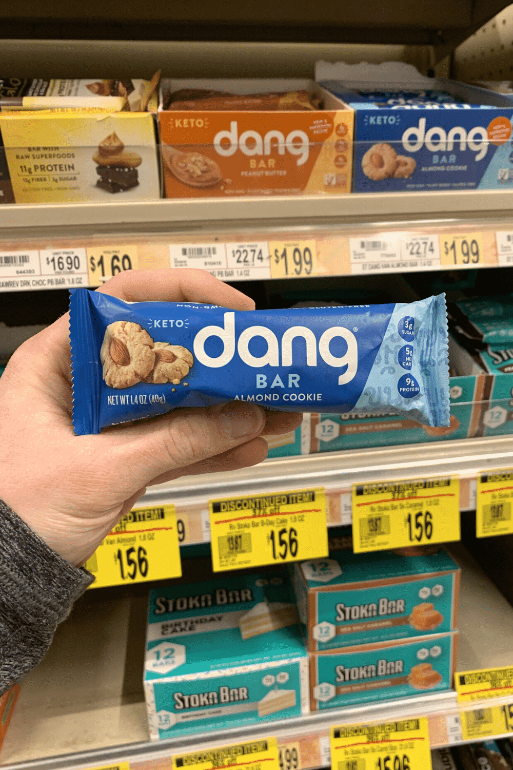 A hand holding a wrapped almond cookie dang bar.