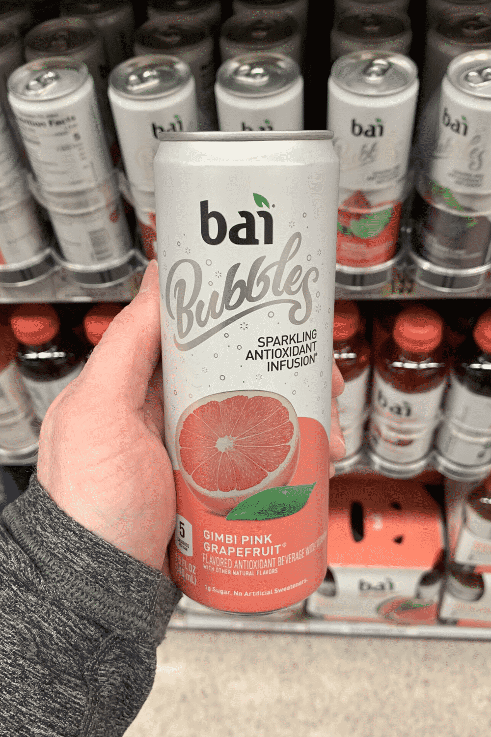 A hand holding a can of gimbi pink grapefruit bai bubbles.