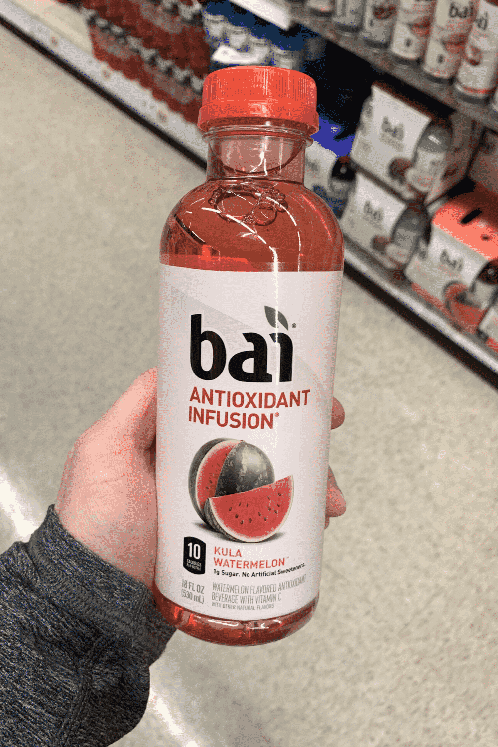 A hand holding a bottle of bai antioxidant infusion kula watermelon flavor.