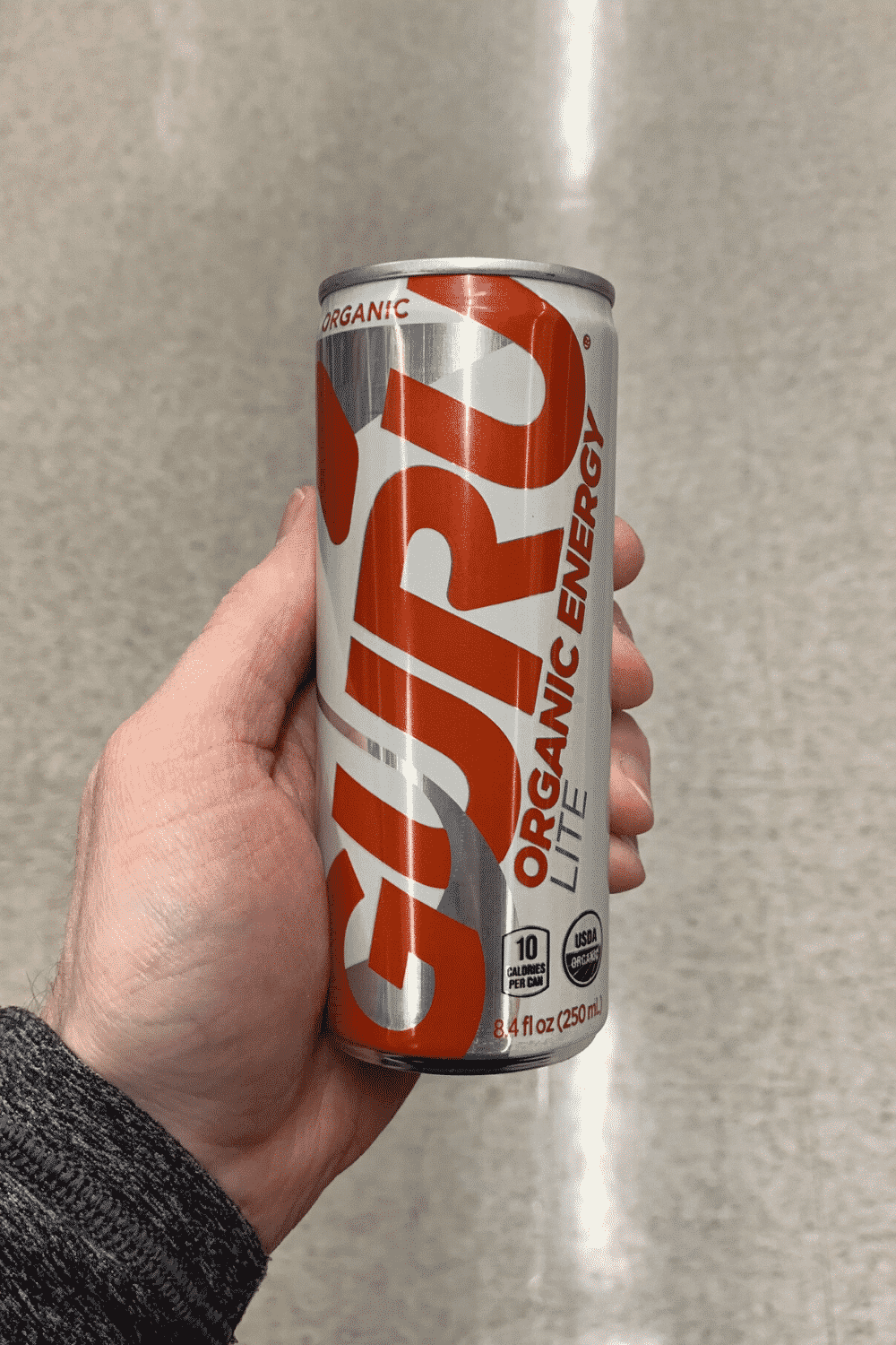 A hand holding a can of Guru lite organic energy drink