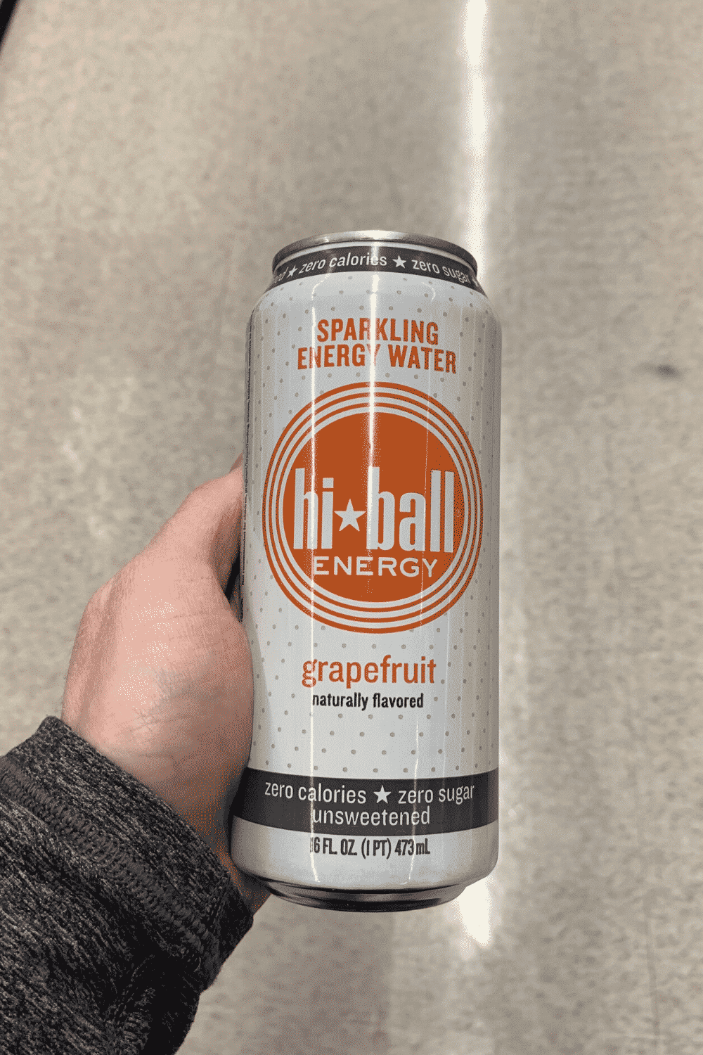 A hand holding a can of hi-ball energy drink grapefruit flavored