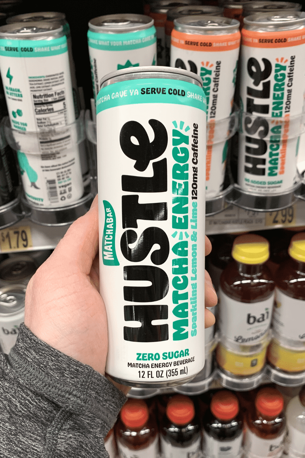 A hand holding a can of Hustle matcha energy sparkling lemon and lime flavor