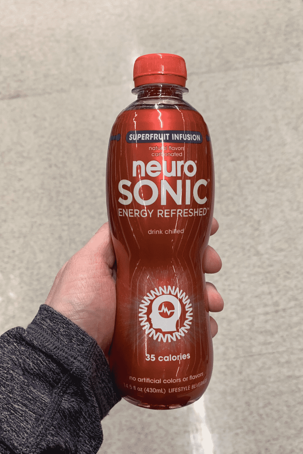 A hand holding a bottle of neuro sonic super fruit infusion