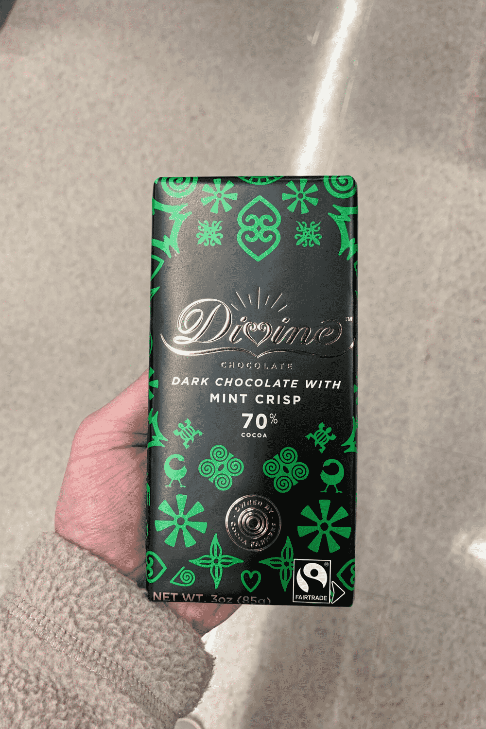 A hand holding a Divine dark chocolate with mint crisp bar