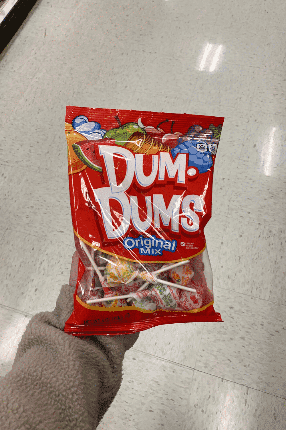 A hand holding a bag of Dum Dums original mix