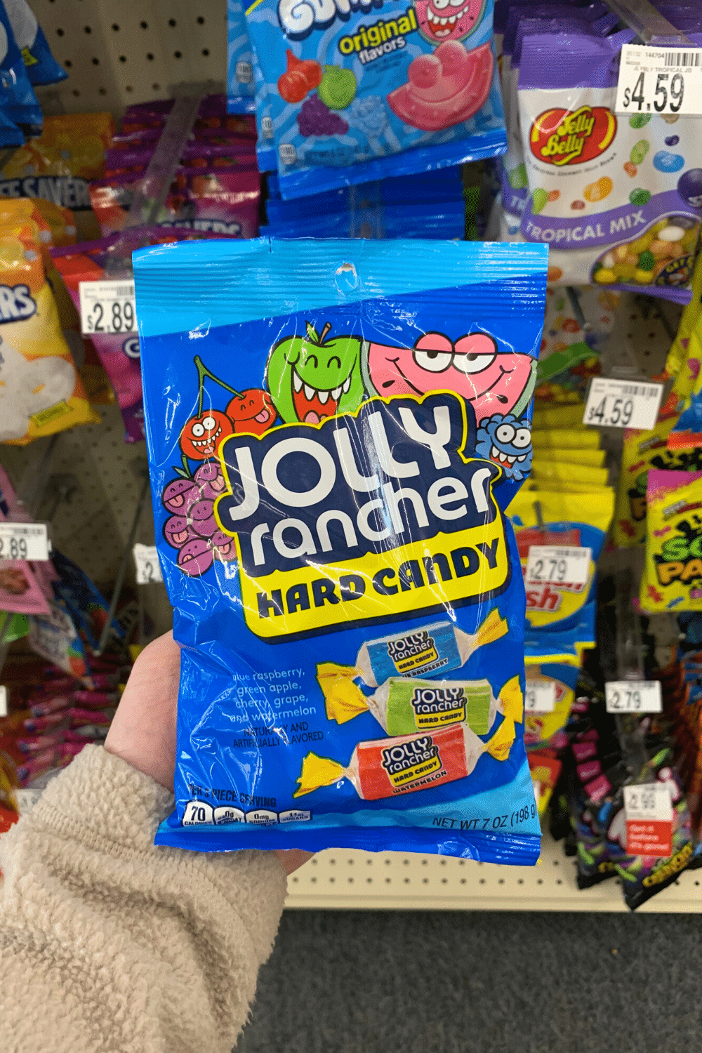 A hand holding a bag of Jolly Rancher hard candy