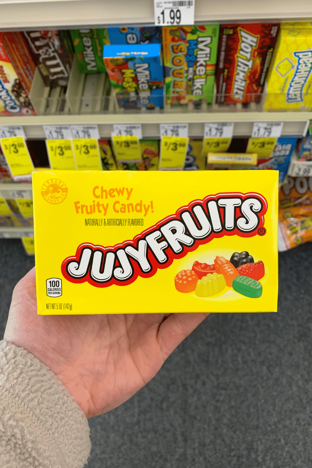 A hand holding a box of Jujyfruits