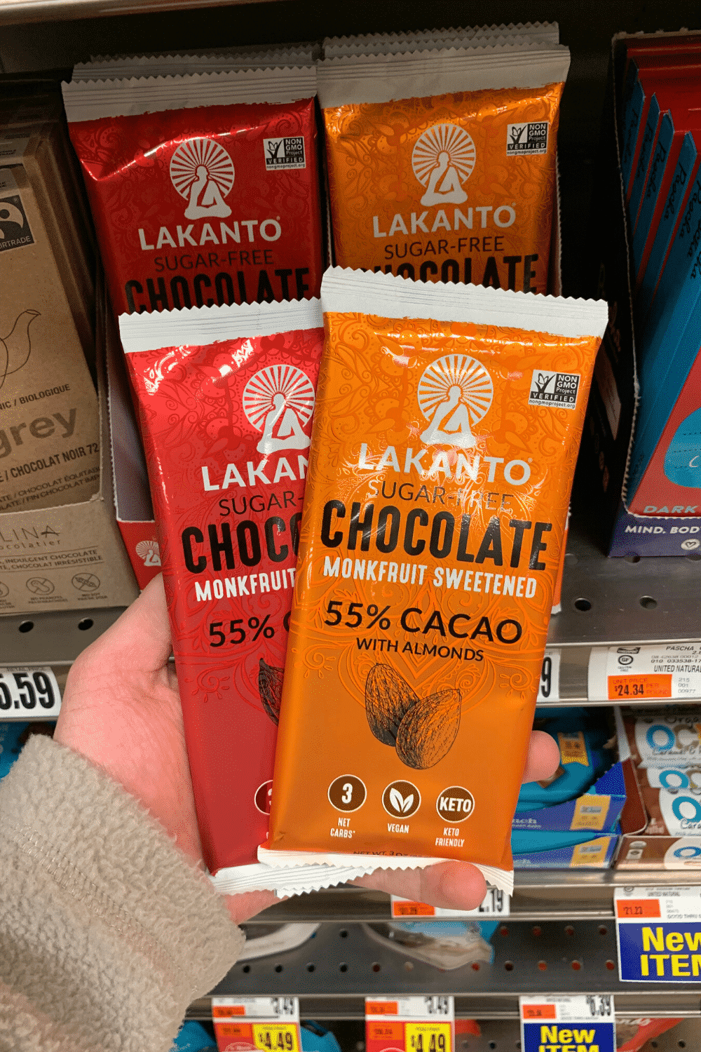 A hand holding Lecanto sugar free chocolate bar and chocolate with almonds bar