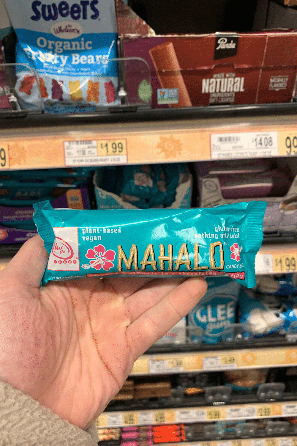 A hand holding a Mahalo vegan candy bar.