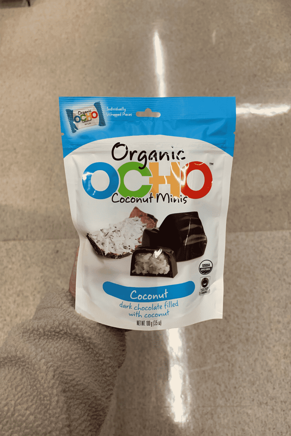 A hand holding a package of OCO coconut minis