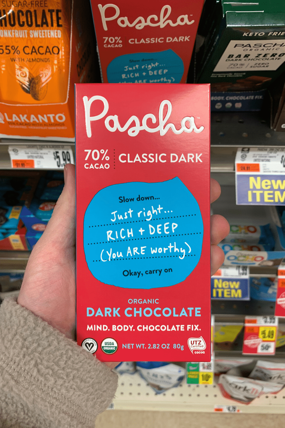 A hand holding a Pascha classic dark chocolate bar