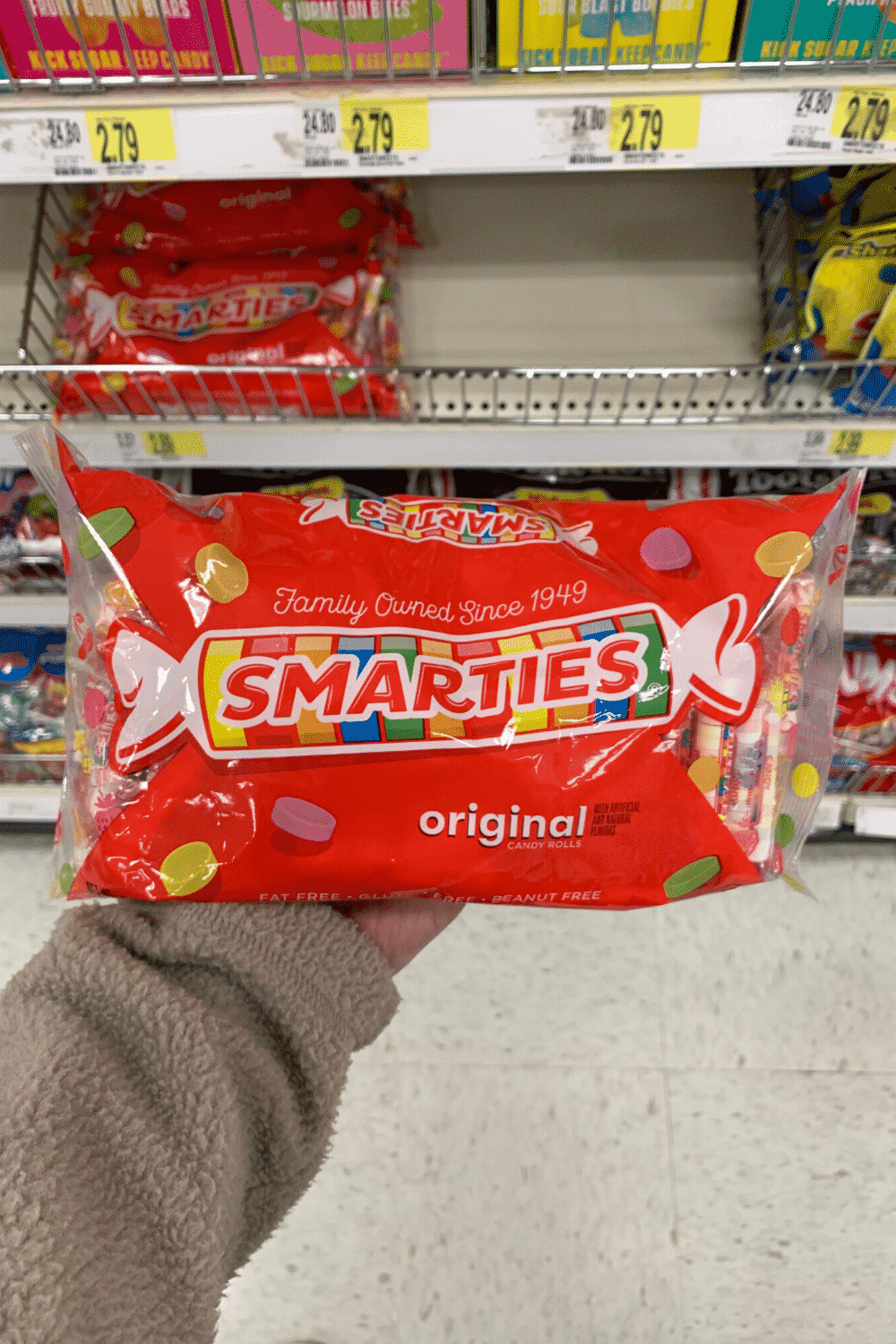 A hand holding a bag of smarties