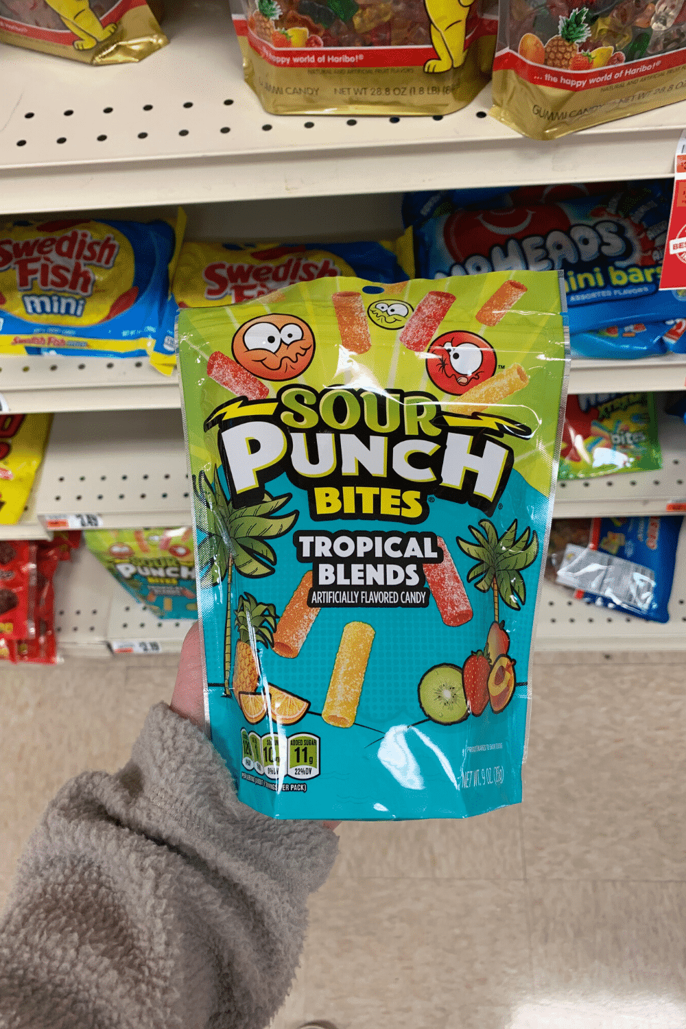 A hand holding a bag of sour Punch bites tropical blends