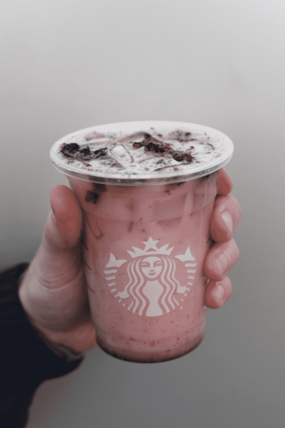 A hand holding Starbucks vegan violet drink.