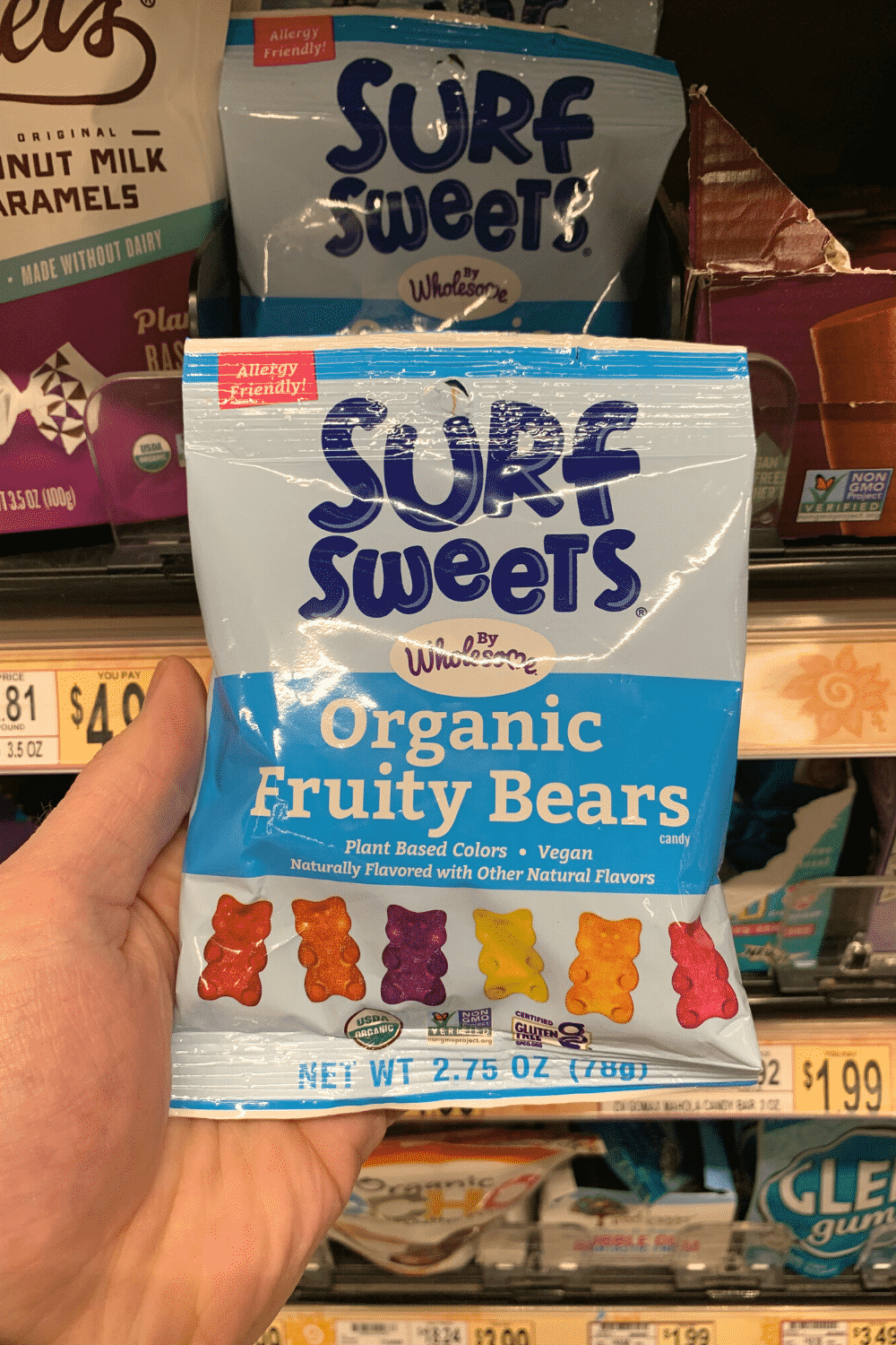 A hand holding a bag of Surf Sweets organic fruity bears