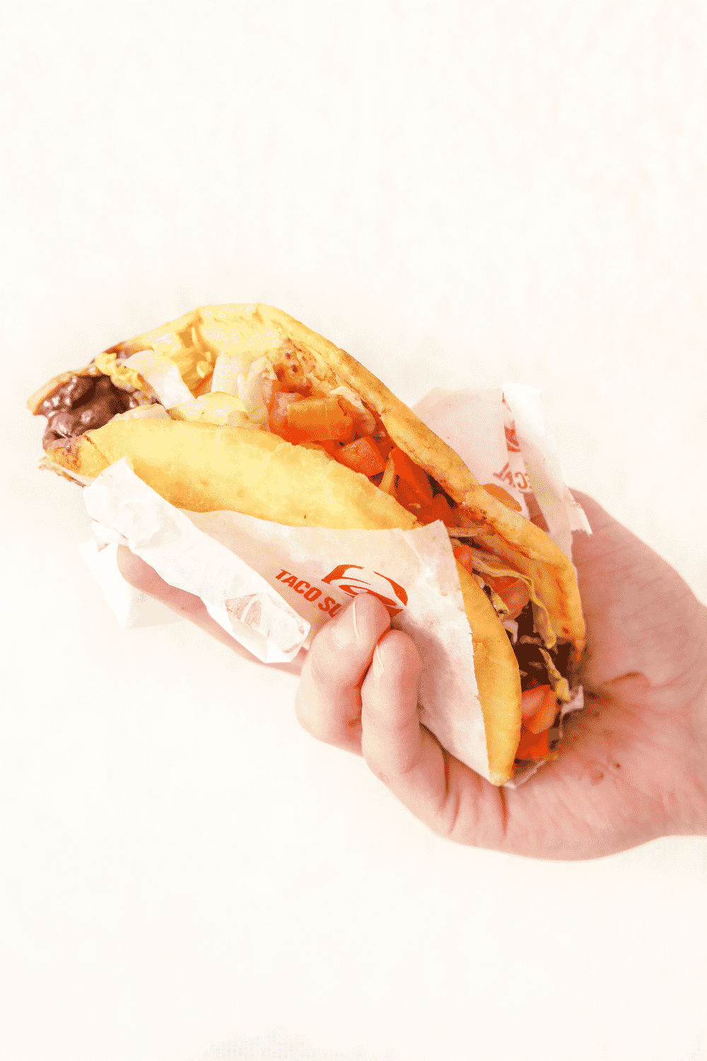 A hand holding a Taco Bell black bean Chalupa