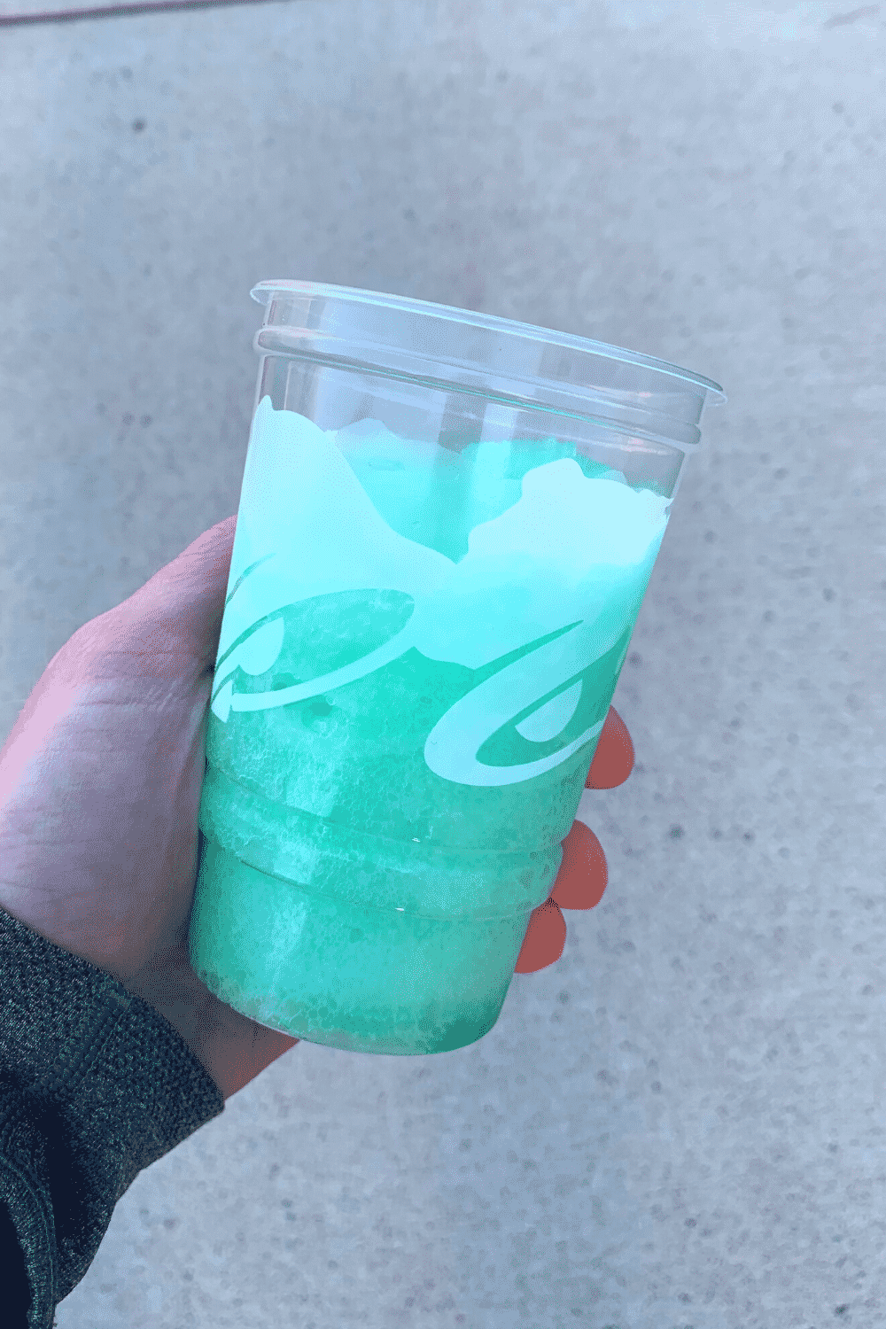 A hand holding a Taco Bell Baja Blast Freeze drink.