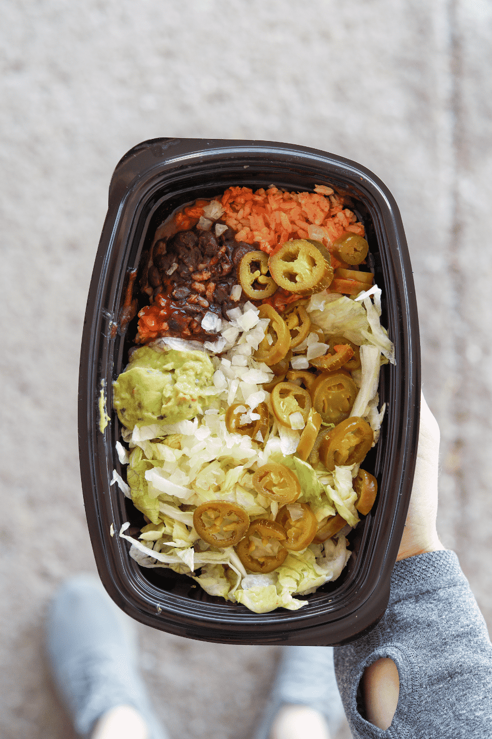 A hand holding a container of Taco Bell veggie power bowl