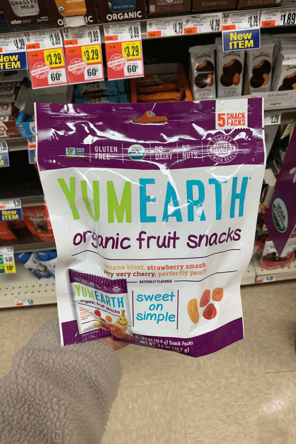 A hand holding a bag of YumEarth organic fruits snacks