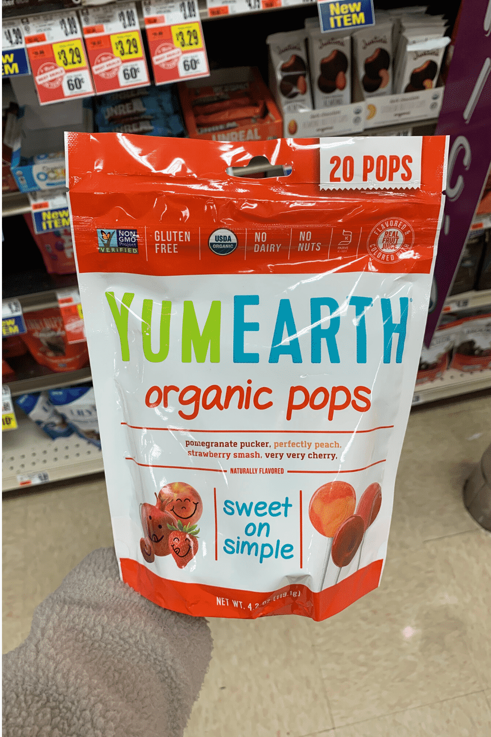 A hand holding a bag of YumEarth organic Pops