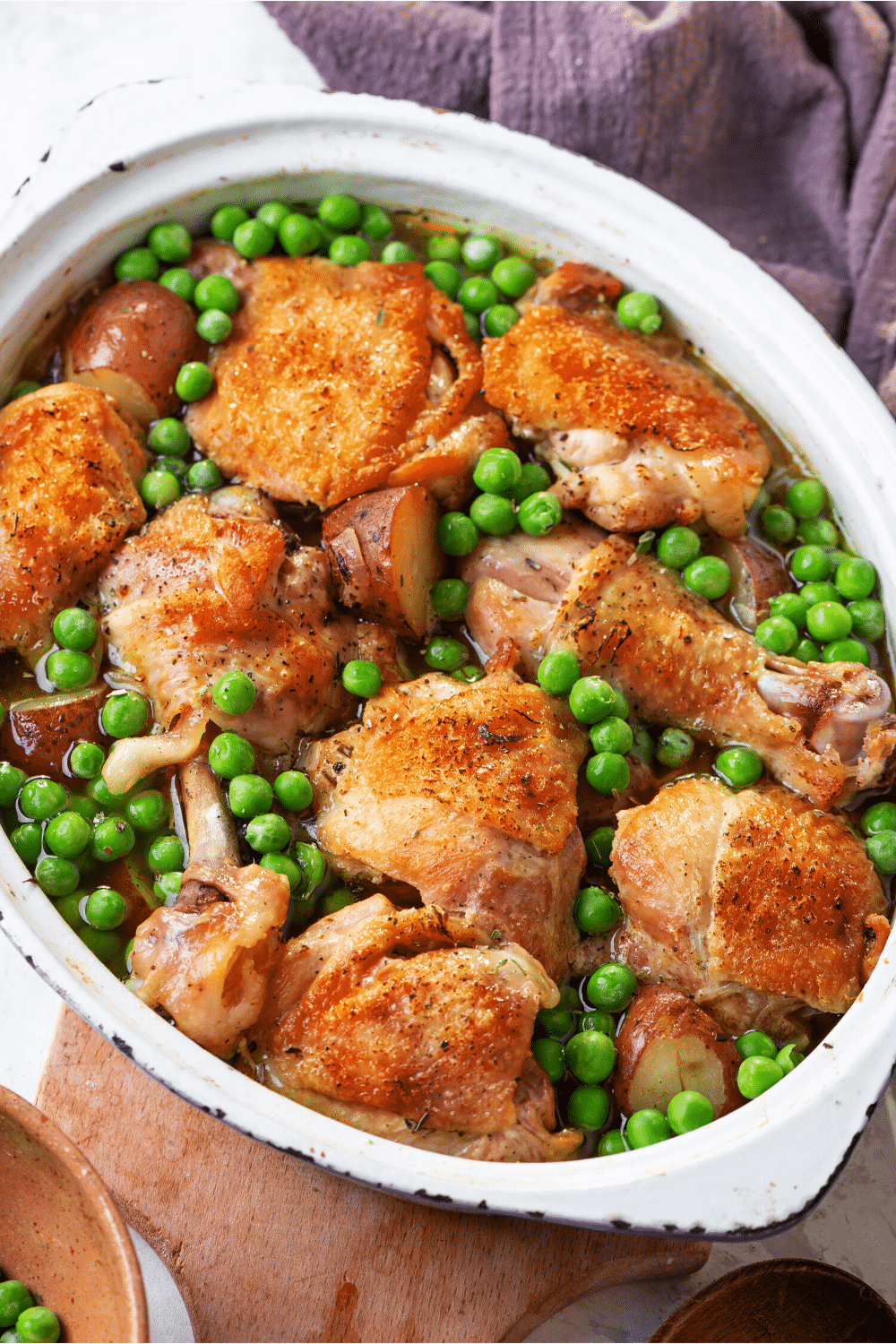 A pot filled with chicken thighs and legs and peas.