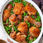 A pot with chicken thighs and peas in it.