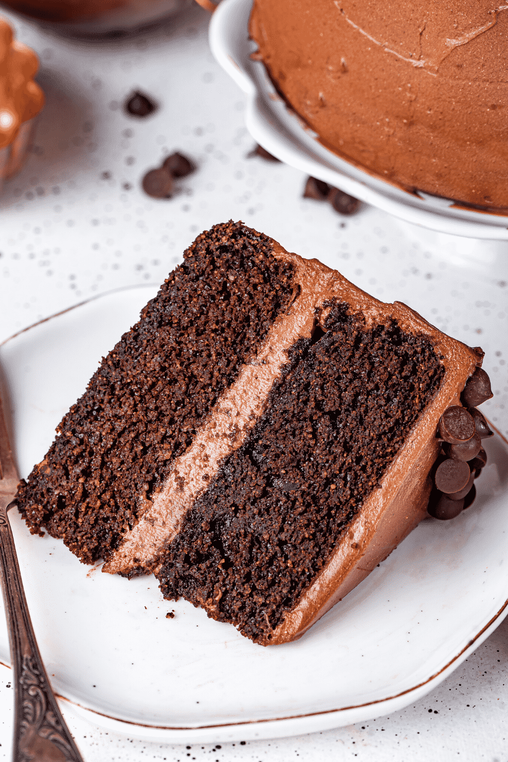 A slice of chocolate cake lying on its side on a white plate.