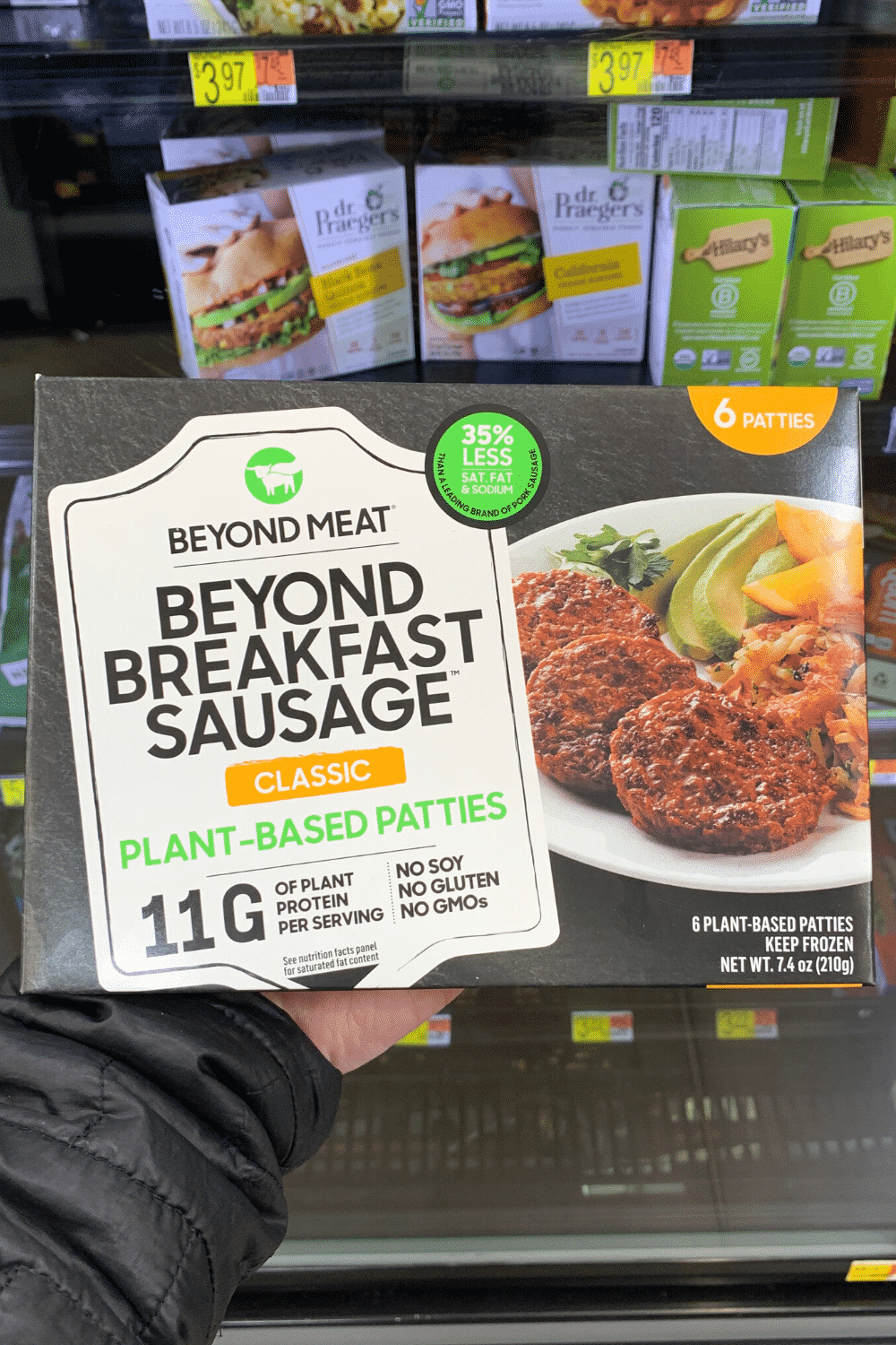 A hand holding beyond meat beyond breakfast sausage plant-based patties.