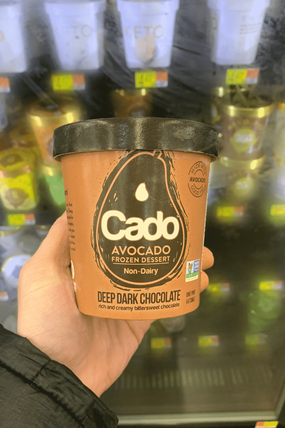 A hand holding Cado avocado frozen dessert nondairy deep dark chocolate ice cream