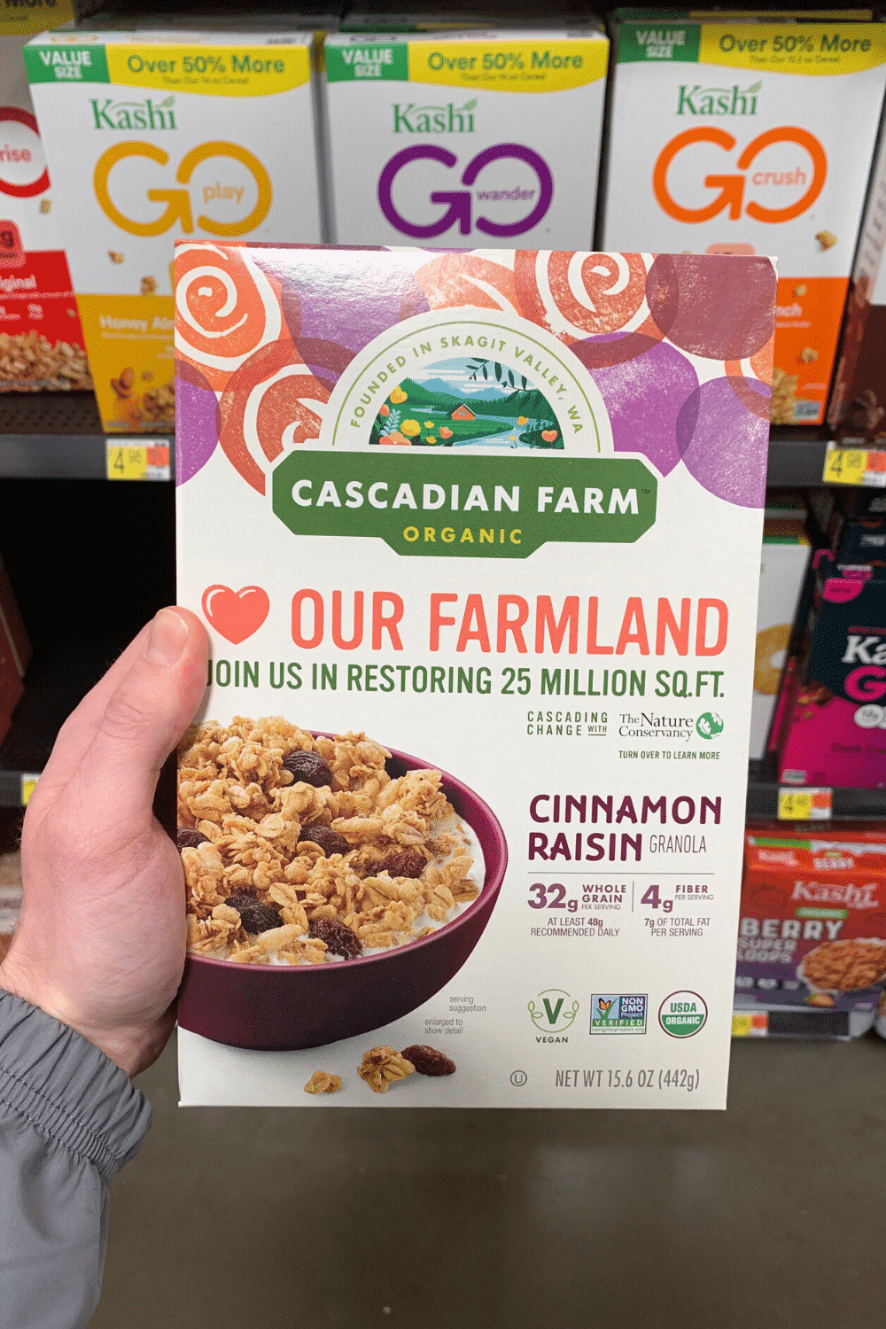 A hand holding Cascadian Farm cinnamon raisin granola.