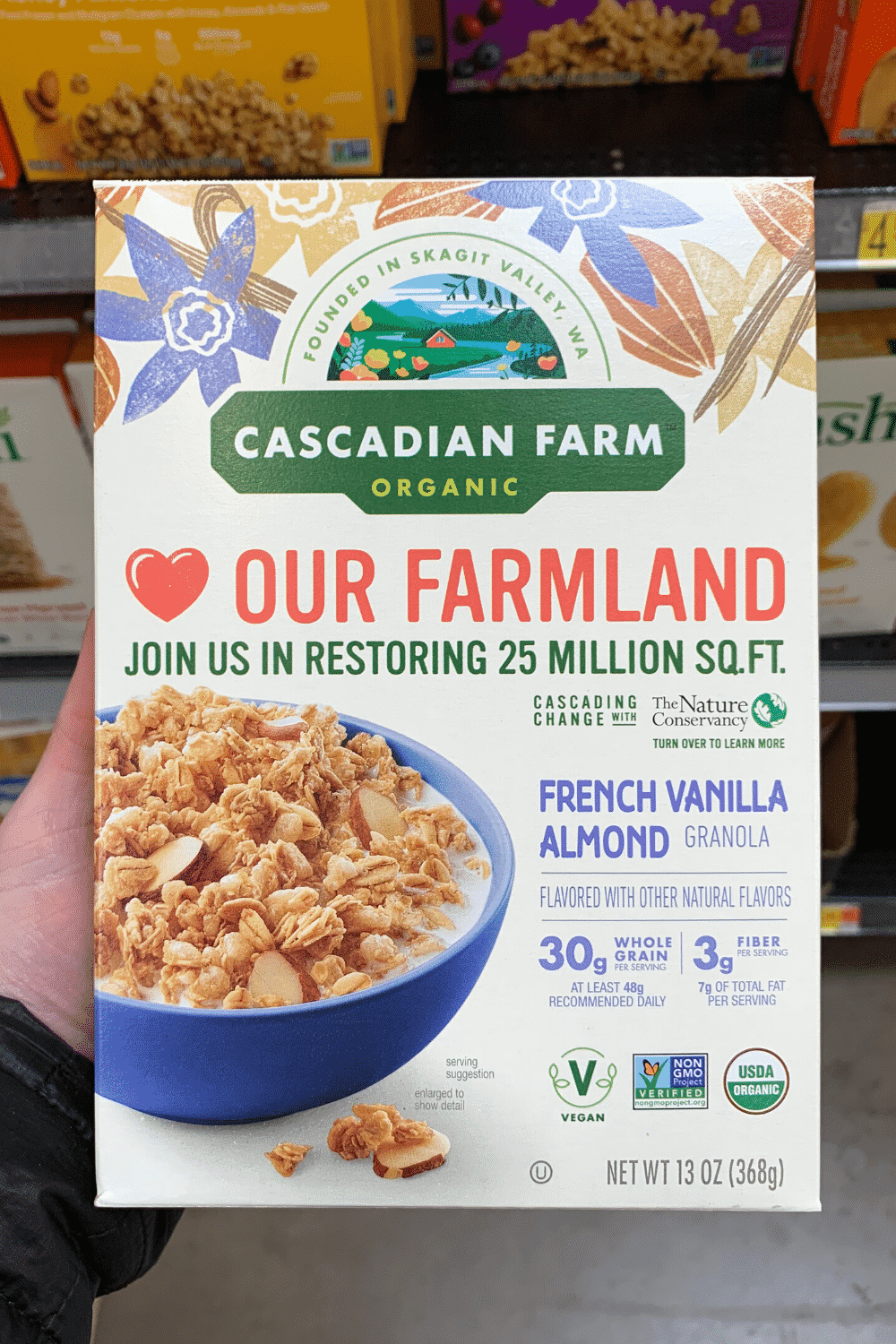 A hand holding Cascadian Farm French vanilla almond granola.