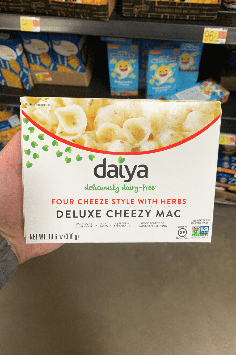 A hand holding Daiya four cheese style with herbs deluxe cheesy Mac.