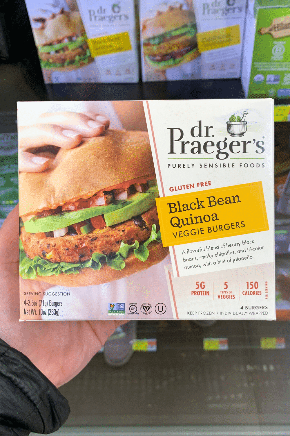 A hand holding Dr. Prager's black bean quinoa veggie burgers.
