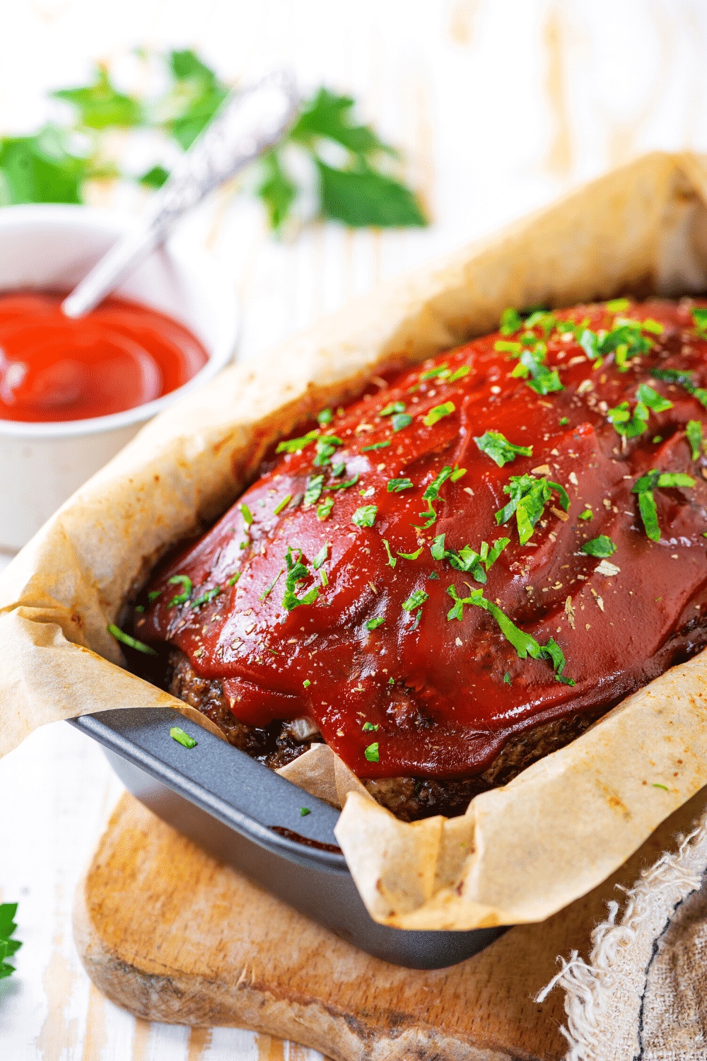 A whole meatloaf on a piece of parchment paper in a loaf pan.