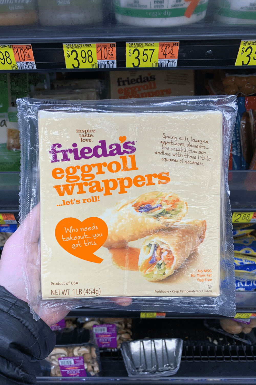 A hand holding Frieda's egg roll wrappers.