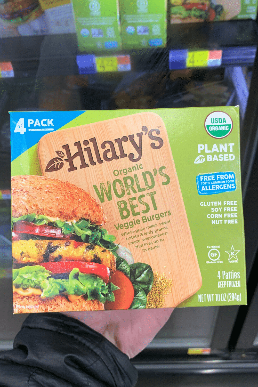 A hand holding Hillary's worlds best plant-based veggie burgers.