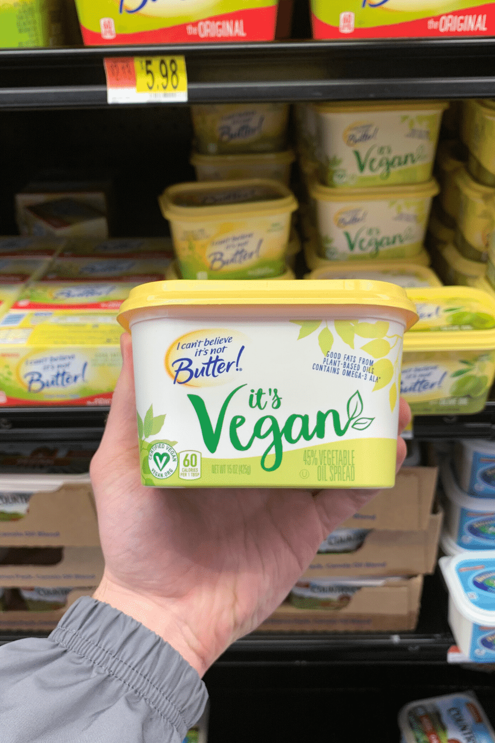 A hand holding I can't believe it's not butter it's vegan.