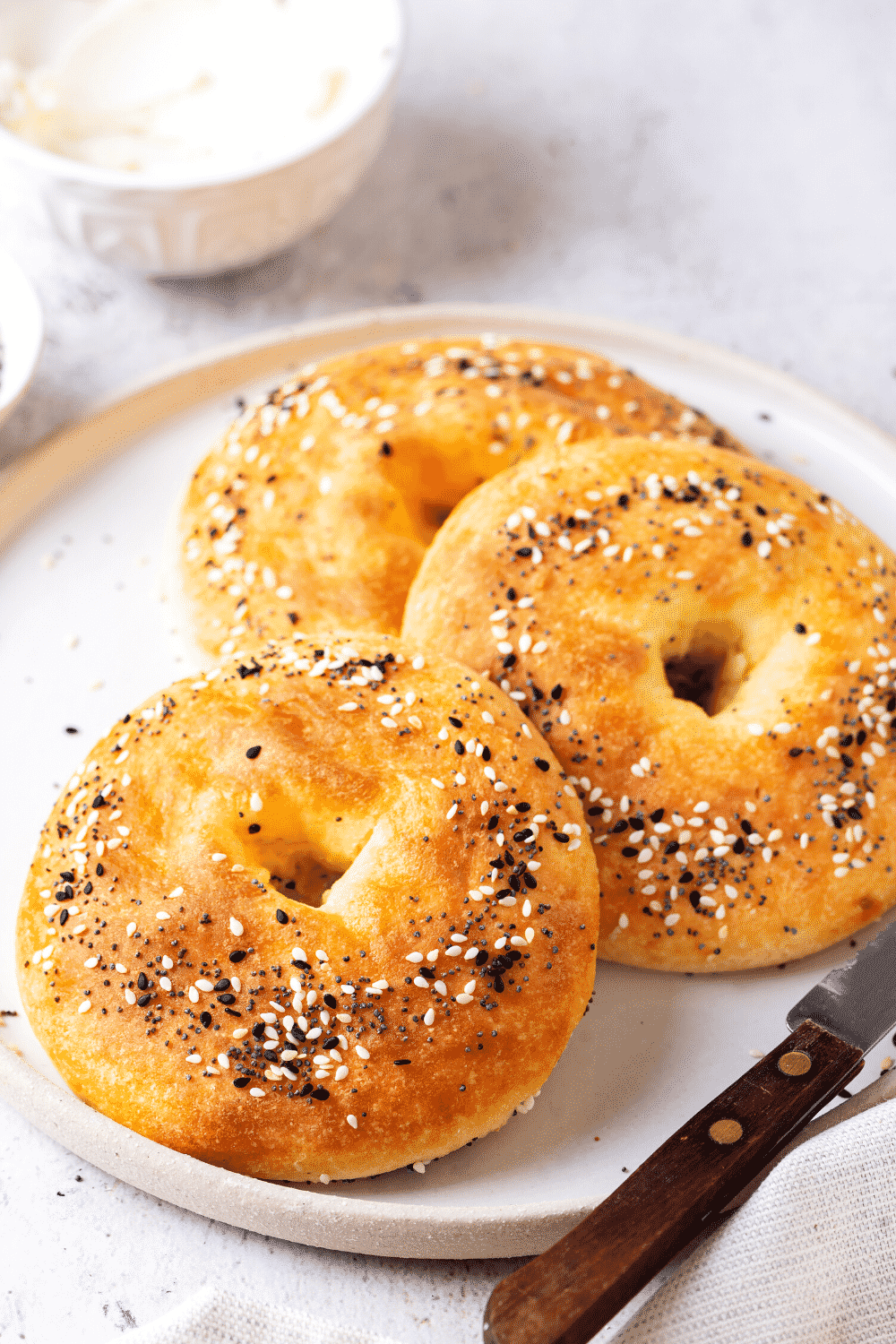 A white plate with three bagels on it overlapping one another.