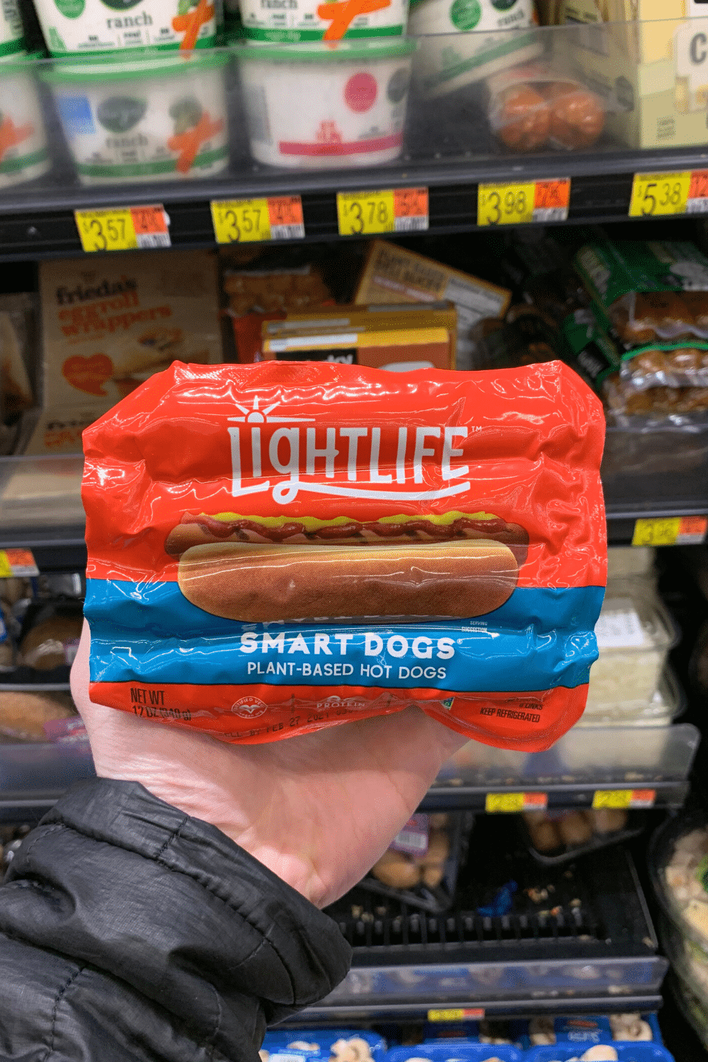 A hand holding light life smart dogs plant-based hotdogs