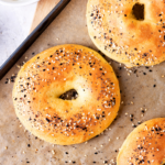 A few bagels on a baking sheet lined with parchment paper.