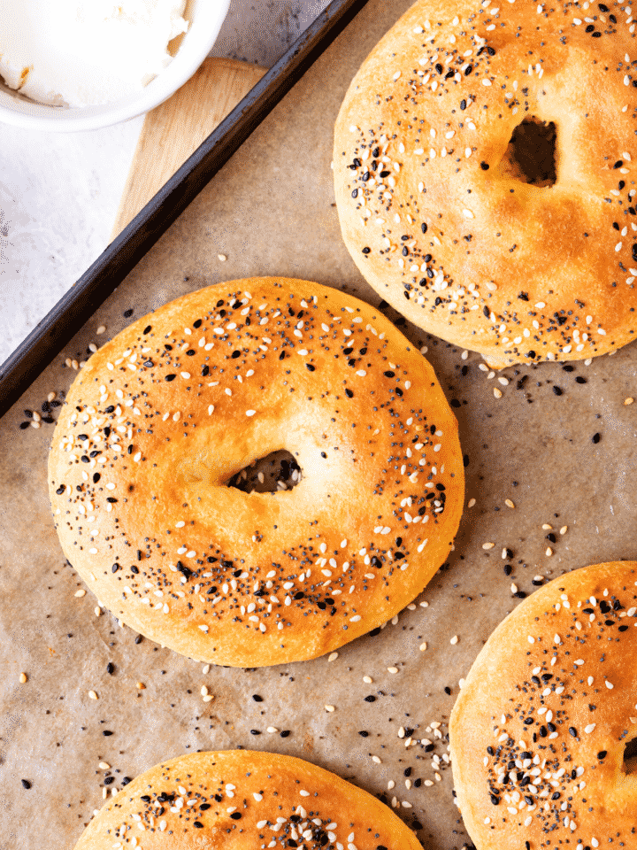 A few bagels on a baking sheet lined with parchment paper.