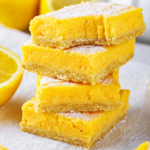 A stack of for keto lemon bars with a bite out of the front of the top lemon bar.