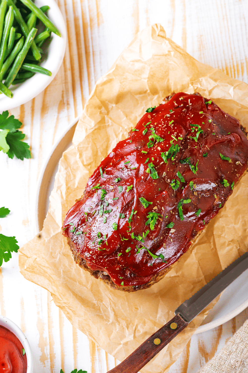 A whole meatloaf on a piece of parchment paper on a white plate.