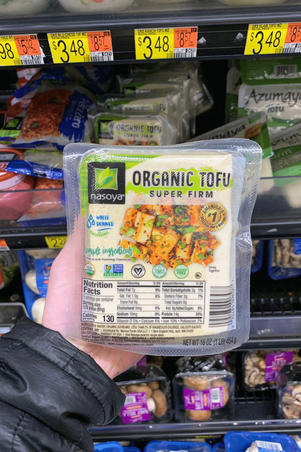 A hand holding nasoya organic tofu super firm