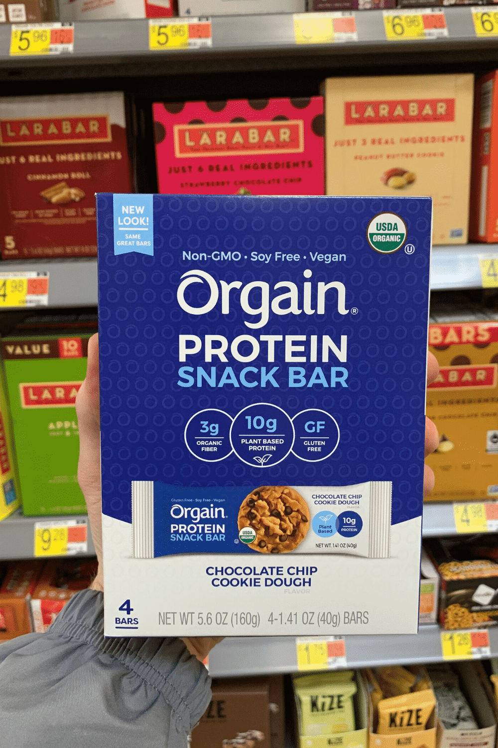 A hand holding Orgain protein snack bar chocolate chip cookie dough.
