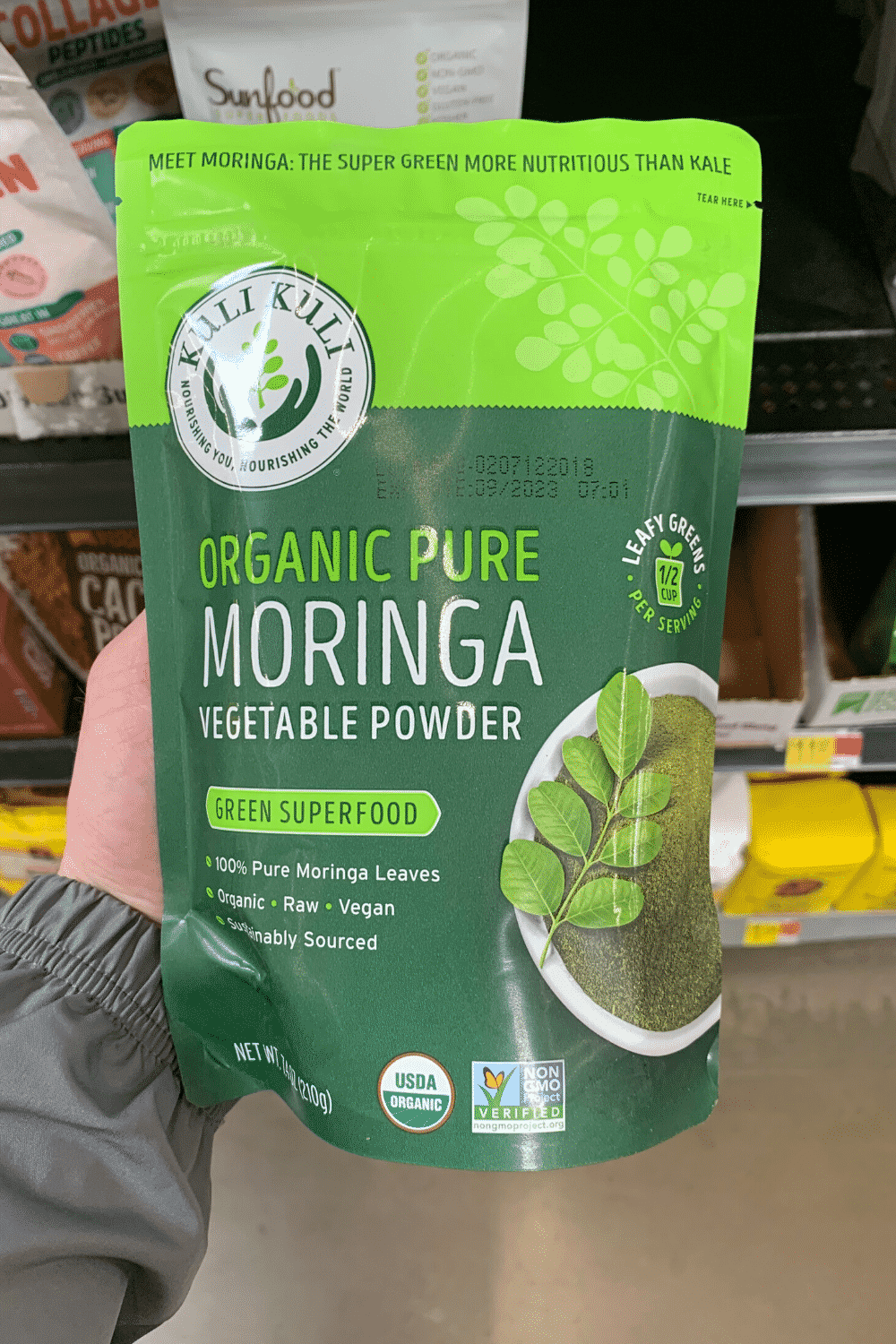 A hand holding organic pure moringa vegetable powder green super food.