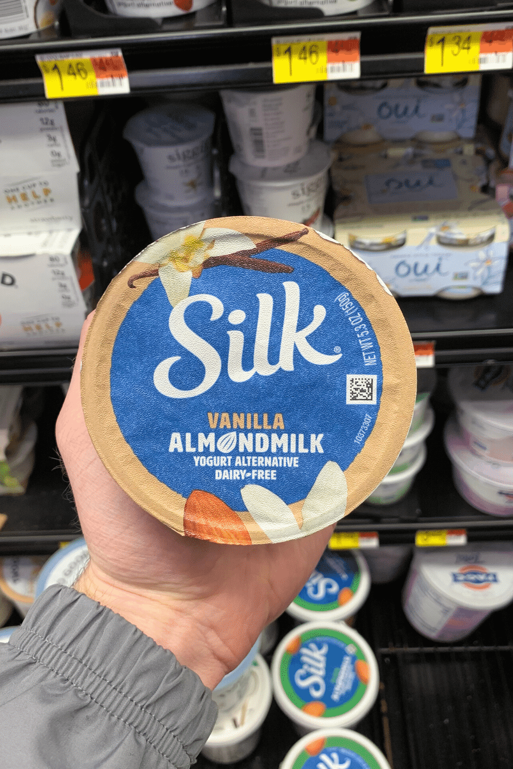A hand holding a silk vanilla almond milk container.