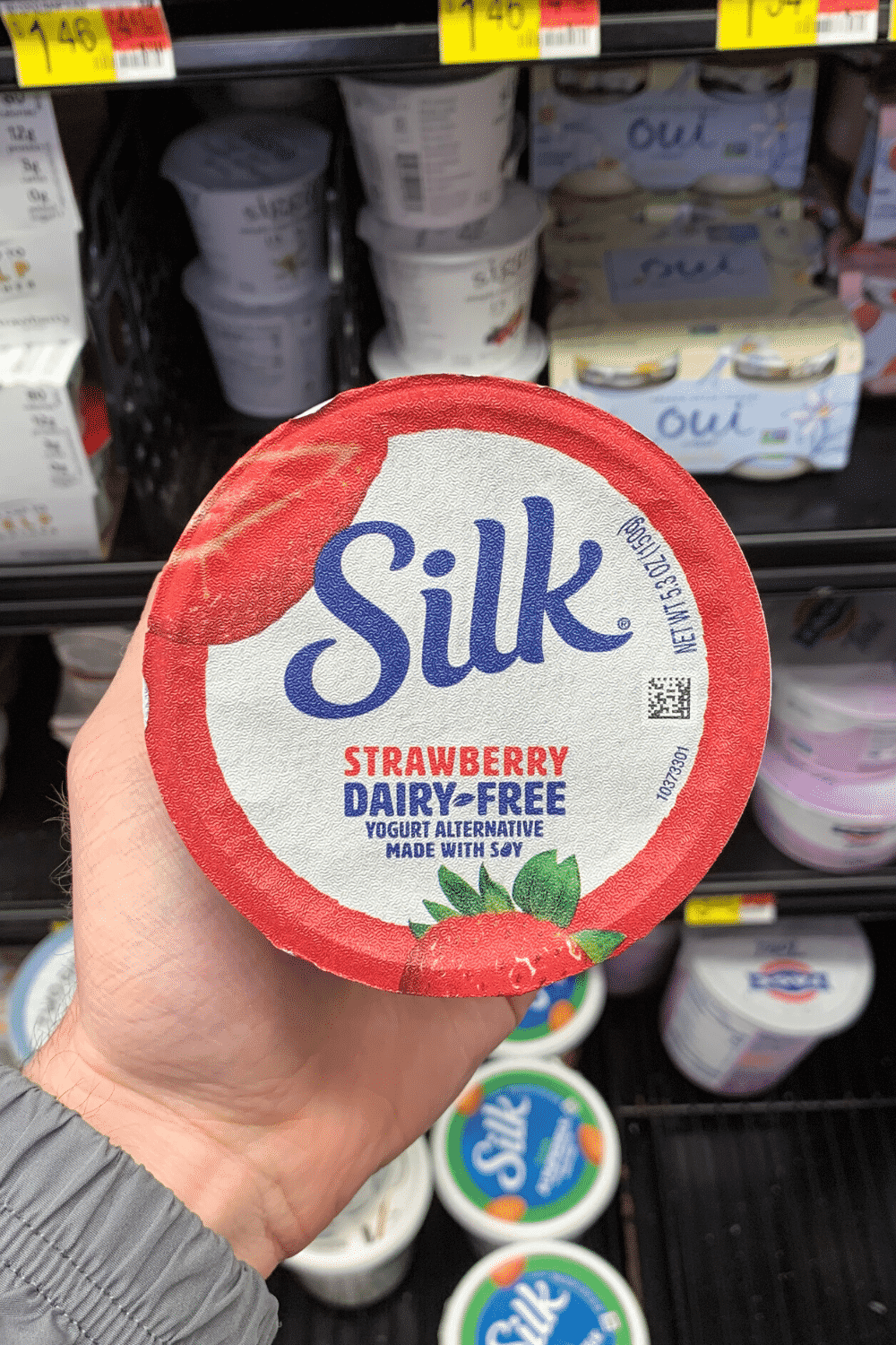 A hand holding a container of silk strawberry dairy free.