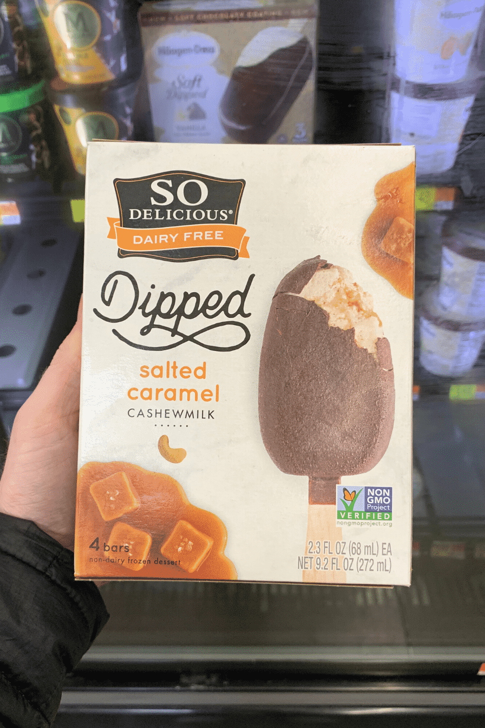 A hand holding so delicious dairy free dipped salted caramel cashew milk ice cream bars.